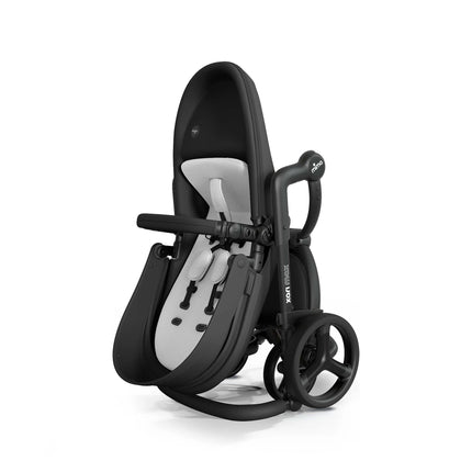 mima xari max Black stroller folded upright on its rear wheels with the Stone White pad still fitted