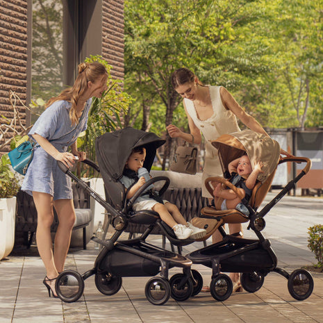 mima creo city strollers in Black and Mocha side by side as two parents walk with their toddlers