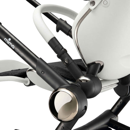 Close-up of the folding chassis joint and champagne accent hub on the mima creo White stroller