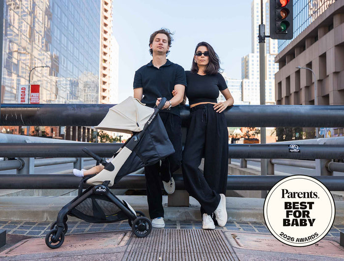 Parents in the city with a child in a mima miro Black compact travel stroller with a 2026 award badge