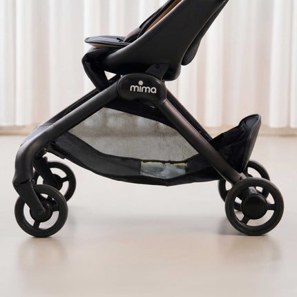 Mesh under seat storage basket on the mima miro Black compact stroller seen from the side