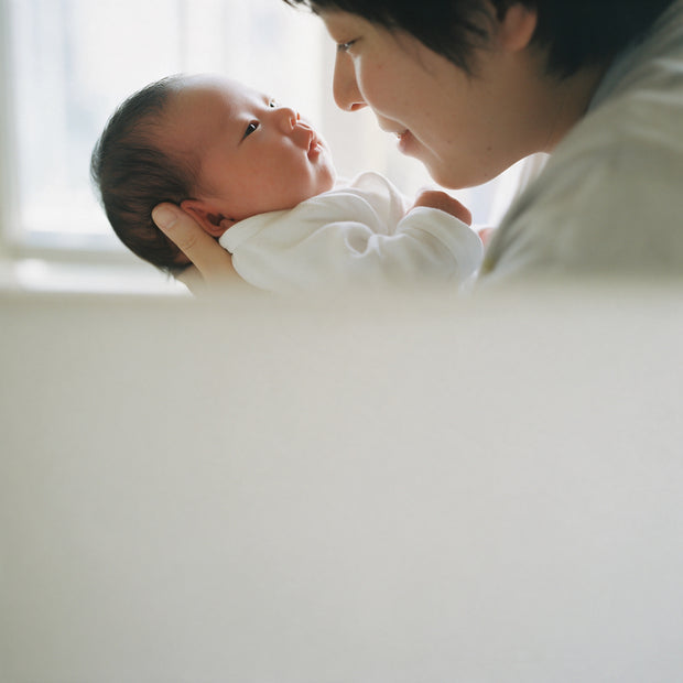 A parent holds a newborn and looks at their face